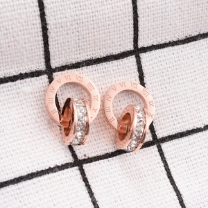 Close-up of rose gold double ring earrings with Roman numerals and sparkling crystals