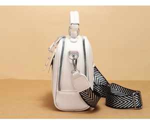 Dettaglio borsa a tracolla beige con trama litchi e tracolla in tessuto a righe