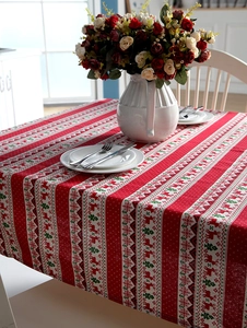 Detail of red Christmas tablecloth with reindeer and tree print for festive table decor