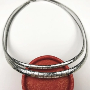 Macro shot of silver stainless steel collar necklace with wave sand geometric texture