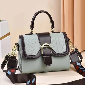 Detalle de bolso verde menta con textura de cocodrilo y correa tejida geométrica