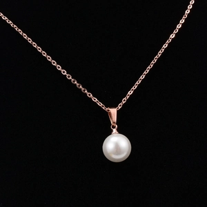 Close-up of polished rose gold necklace featuring a radiant white pearl pendant on a thin chain