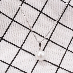 Detail shot of a minimalist silver chain necklace featuring a single round white pearl