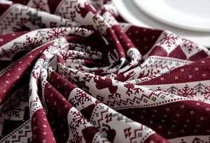 Close-up of red Christmas fabric with white reindeer and snowflake woven patterns