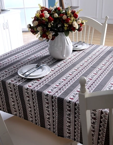 Detail of Christmas tablecloth featuring reindeer, pine trees, and snowflakes on a table