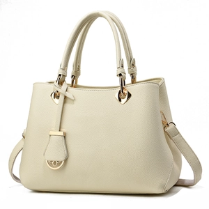 Close-up of beige lychee grain leather handbag with gold horseshoe metal decoration