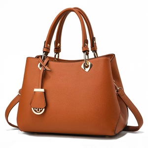Detailed side view of orange leather handbag with heart charm and golden rivets