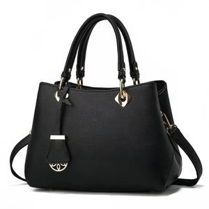 Detailed view of black litchi grain leather texture and golden floral metal charm on handbag