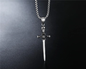 Detailed close-up of punk style skull dagger pendant on a steel chain necklace