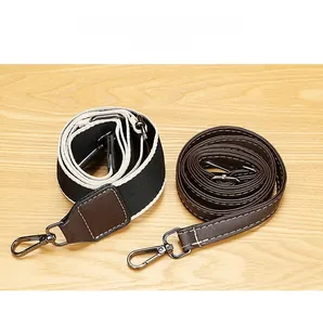 Détail d'une bandoulière large en tissu et d'une fine en cuir avec crochets gris foncé