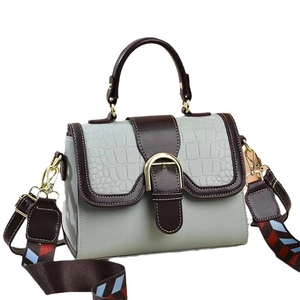 Bolso azul y marrón con solapa de cocodrilo y correa tejida de colores vivos