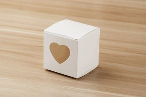 Détail d'une boîte cadeau blanche en papier avec fenêtre en forme de cœur sur bois