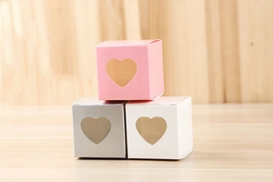 Détail de boîtes cadeaux cubiques avec fenêtre en cœur en rose, blanc et gris argent