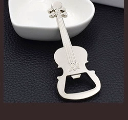 Silver violin-shaped metal bottle opener on black leather surface, close-up creative design