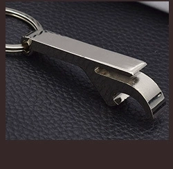 Close-up of a versatile metal bottle opener keychain with polished finish on dark surface