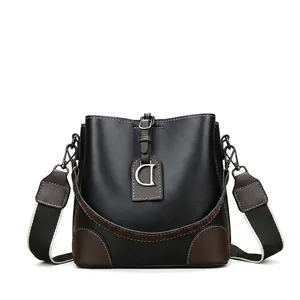 Détail du sac seau bicolore avec bandoulière large et pendentif en métal lettre D