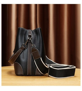 Détail d'un sac seau bicolore avec surpiqûres blanches et bandoulière tissée large