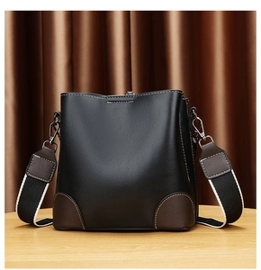 Détail du sac seau en similicuir noir avec patchs marrons et large bandoulière