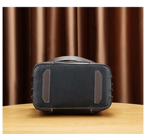 Vue détaillée du fond du sac en cuir noir et marron avec coutures blanches contrastées