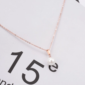 Macro shot of minimalist rose gold necklace featuring a round white pearl pendant