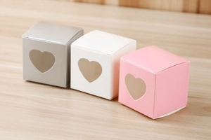 Trois boîtes cadeaux en kraft avec fenêtres en PVC en forme de cœur sur bois