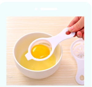 Macro shot of white plastic egg yolk separator resting on bowl with egg yolk inside