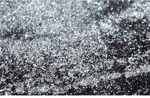 Vue macro d'une poudre à ongles miroir argentée ultra-fine avec un éclat métallique intense