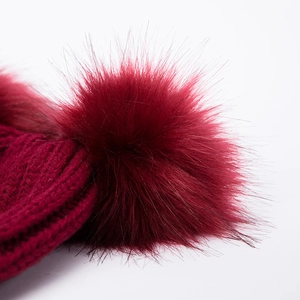 Dettaglio del berretto in maglia rosso scuro con morbido pompon in ecopelliccia soffice