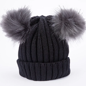 Dettaglio del cappello in maglia a coste nere con due pompon grigi soffici per l'inverno
