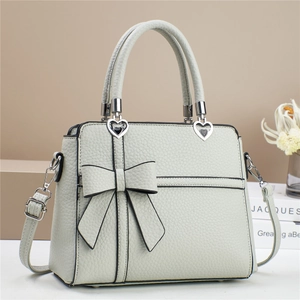 Détail d'un sac en cuir vert menthe avec grand nœud et boucle en métal en forme de cœur