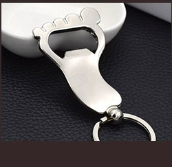 Polished silver foot-shaped bottle opener keychain on a textured black background