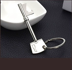 Macro shot of silver key-shaped metal keychain with ring on a textured black surface