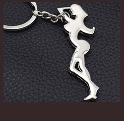 Detail of silver metal keychain with pregnant woman silhouette on leather background