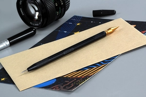 Macro shot of dual-purpose precision scratching pen with golden tip and black knurled handle
