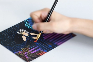 Close-up of a dual-purpose gold scratching tool creating detailed city night art