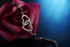 Detail of interlocking heart bracelet with purple zircon on a romantic red rose