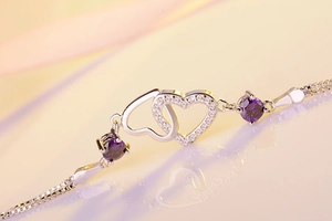Close-up of double heart bracelet with purple zircon stones and polished silver finish