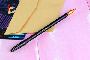 Detailed macro view of the YUELU dual-purpose gold tip scratch pen on pink wood texture