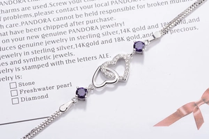 Detail of silver double heart bracelet with purple crystals and sparkling pavé heart