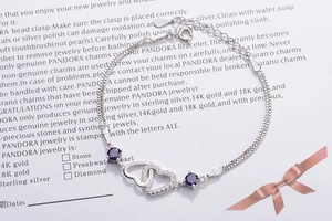 Detail of sterling silver bracelet with purple crystals and double heart pendants