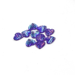 Close-up of purple heart-shaped resin cabochons with iridescent dragon scale texture