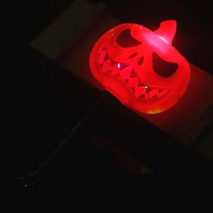 Close-up of glowing red LED Halloween pumpkin wand with black handle for party decor