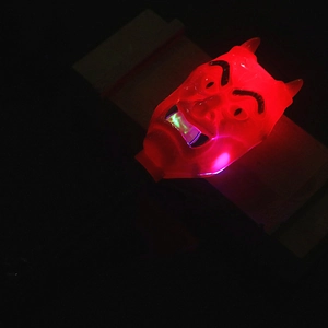 Close-up of glowing red plastic devil mask with horns and green light for Halloween