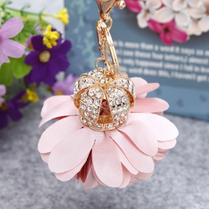 Close-up of pink fabric flower keychain with a gold rhinestone crown center