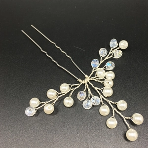 Detail of silver bridal hair pin with white pearls and clear crystals on black background