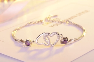 Detail of silver heart bracelet with purple crystals and sparkling white zircons