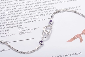 Macro shot of silver snake chain bracelet featuring double heart pendant and purple gems