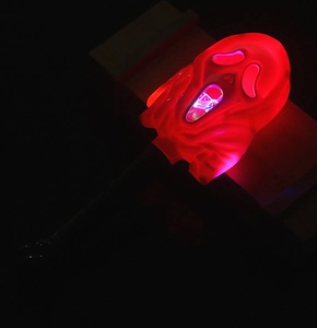 Close-up of glowing LED Ghostface wand with translucent red plastic face and black handle
