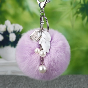 Détail macro du porte-clés pompon en peluche violet avec feuilles d'argent et perles