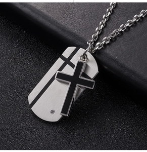 Macro shot of silver metal dog tag and black cross pendant with clear zircon on leather